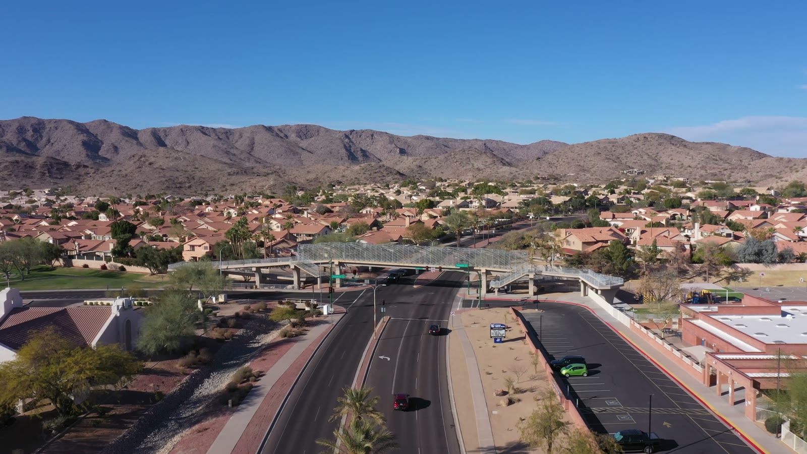 A pedestrian bridge crossing a main road in Ahwatukee, homes and mountains behind