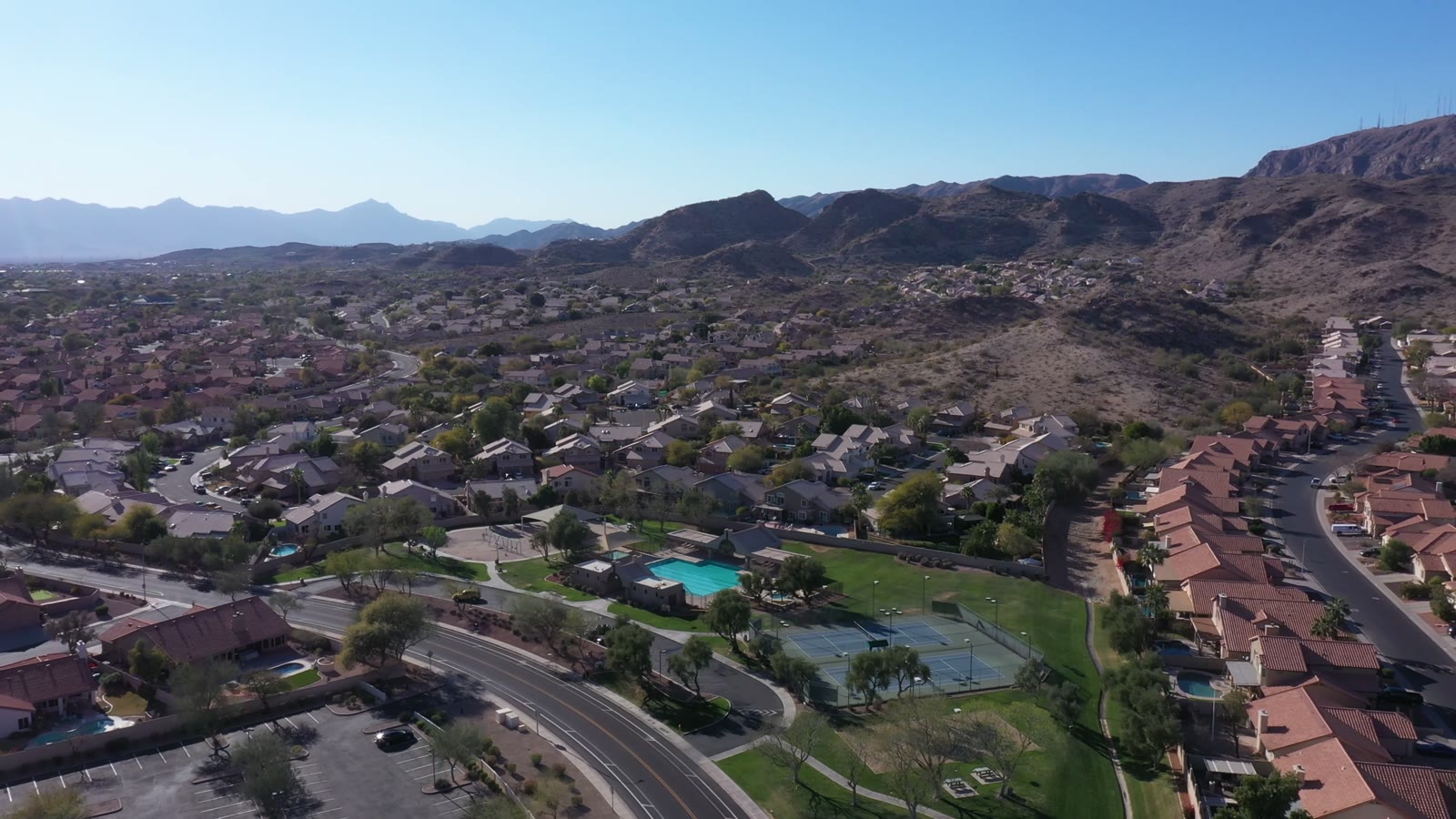 An aerial over Ahwatukee homes and green space, mountains along the skyline