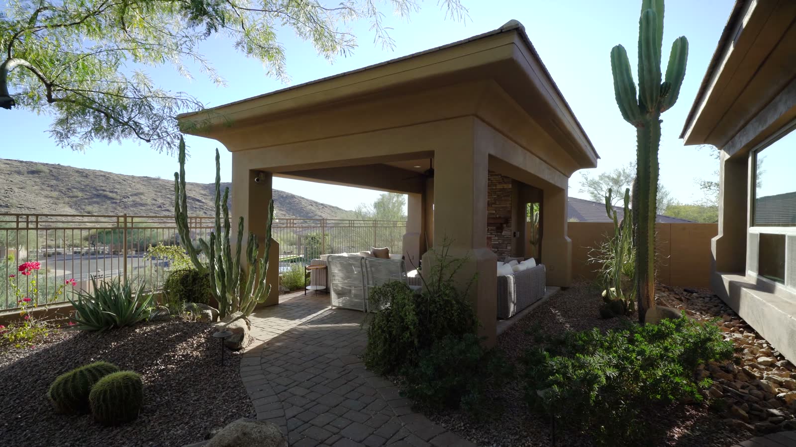 A covered patio with a stone fireplace lit