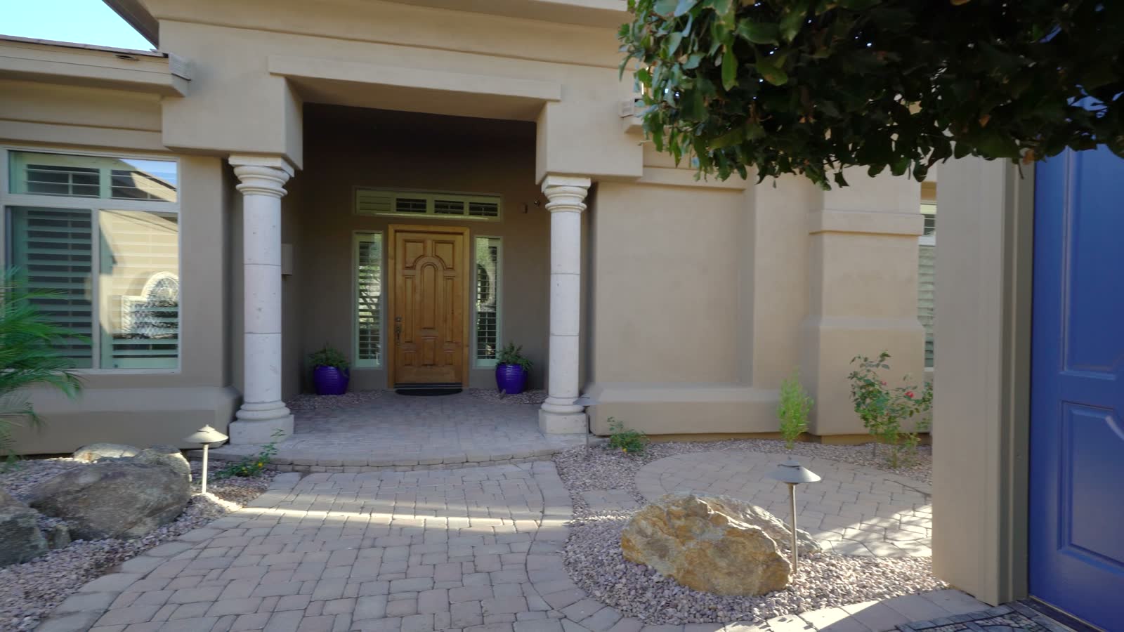 A front entry with a blue door, stone and desert planting