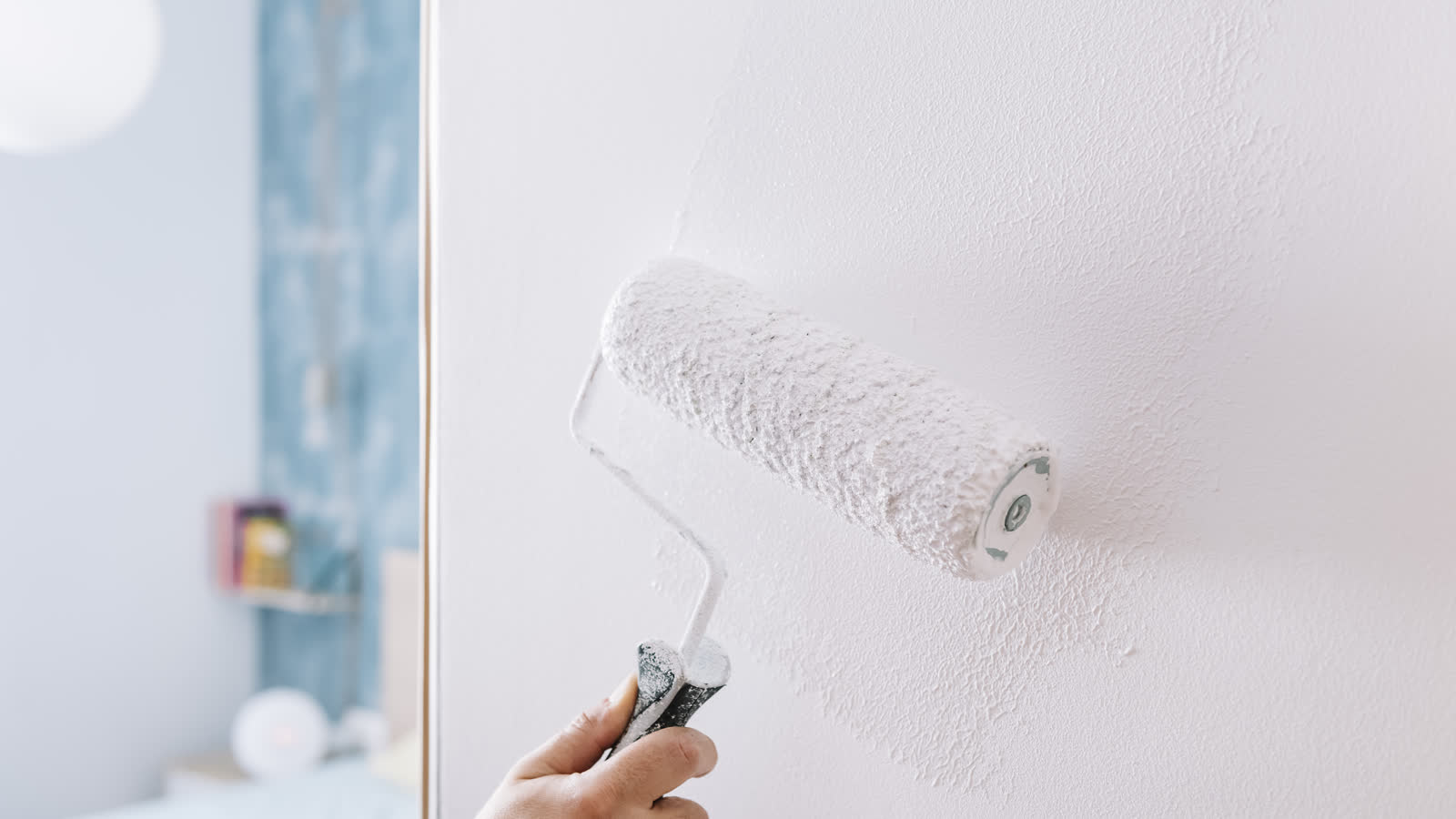 A paint roller applying white paint to a wall