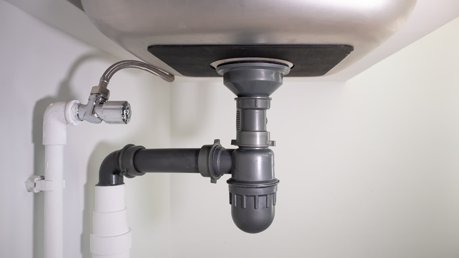 The drain pipe and trap under a kitchen sink