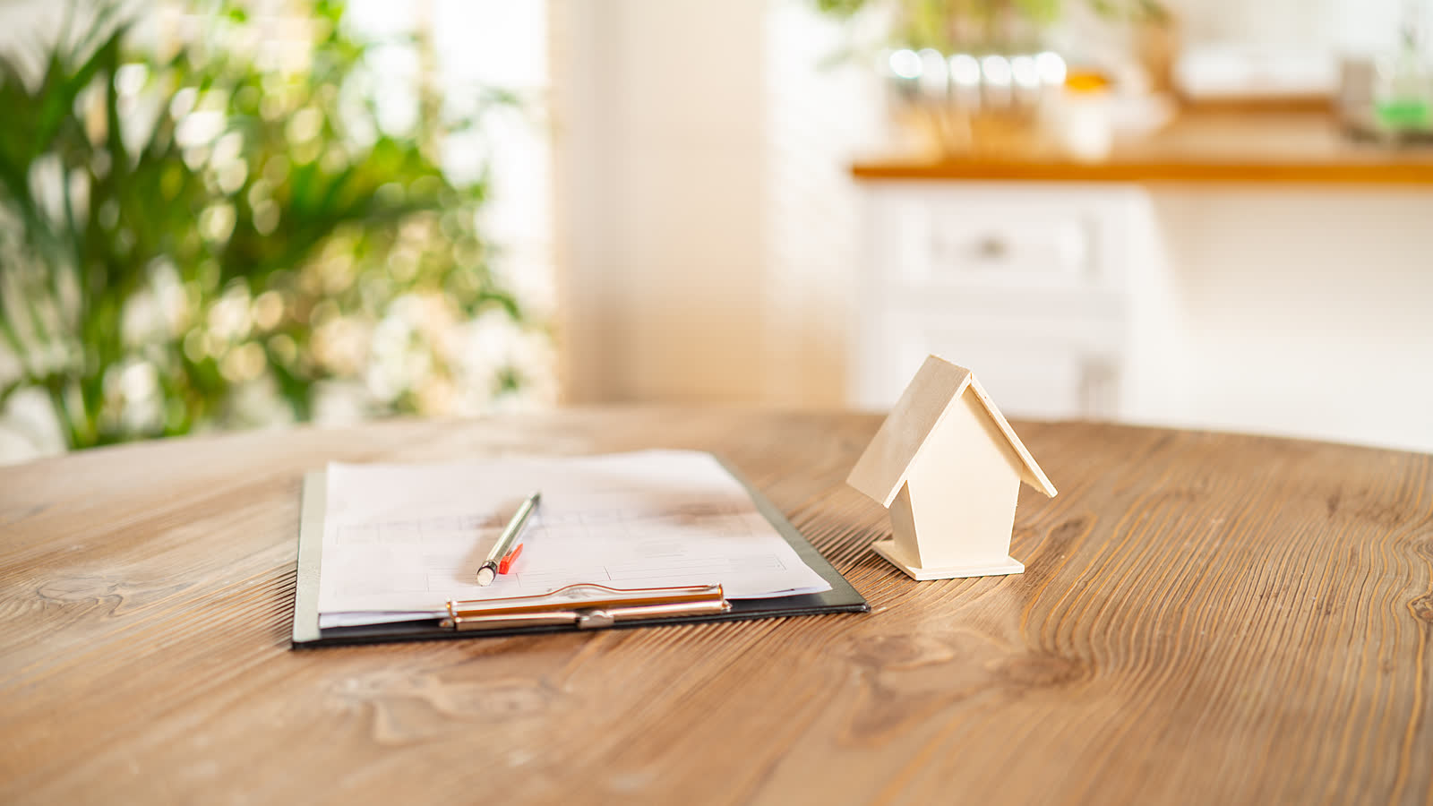 A small wooden model house resting on documents