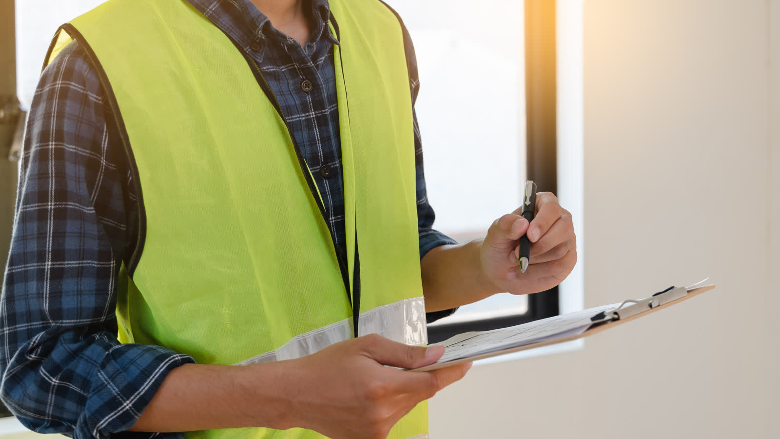 An inspector noting findings on a clipboard while checking a property