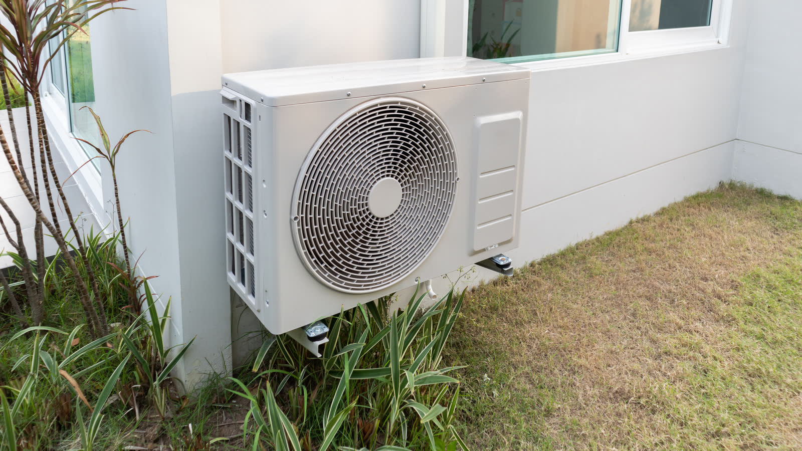 An air conditioning condenser unit installed outside a house