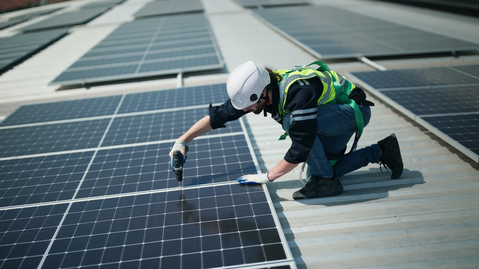 A worker fitting solar panels to a roof