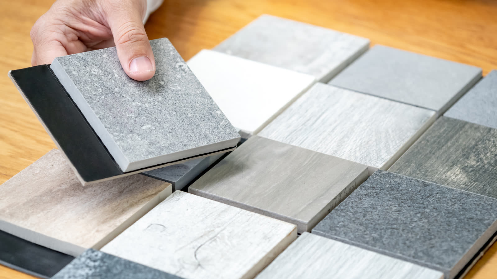 A hand choosing between stone and tile samples